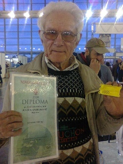 Žuta kutijica desno je spremište za transport matice koje uzgaja za pčelare. Lazar Živković iz sela Bukorovca kod Kragujevca isporučuje pčelinjacima. Diploma u njegovoj desnoj ruci pripada pčelaru Jovici Anđelkoviću koji prodaje Lazarove matice.